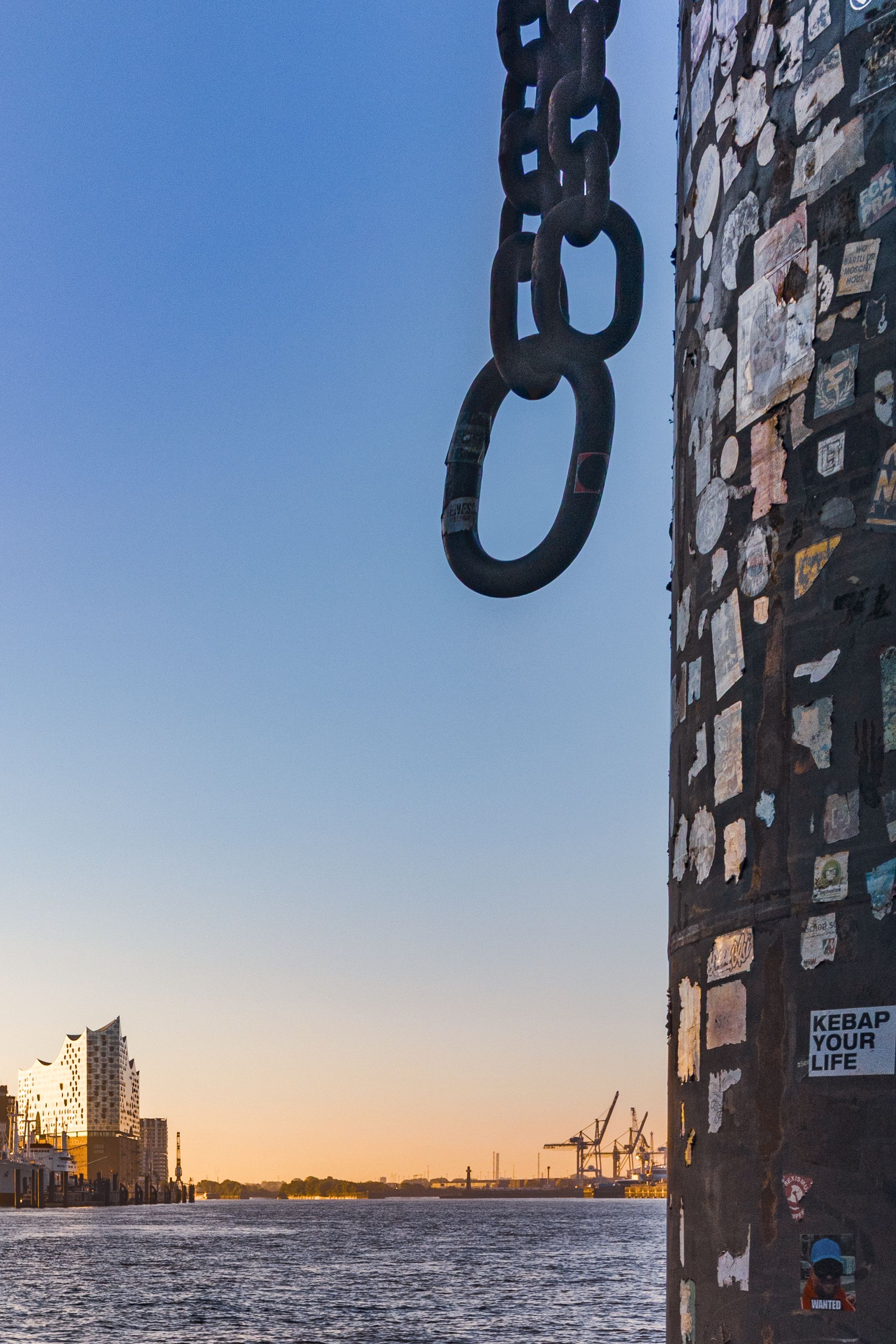 Schwere Kette vor Mauer und Hafenlandschaft