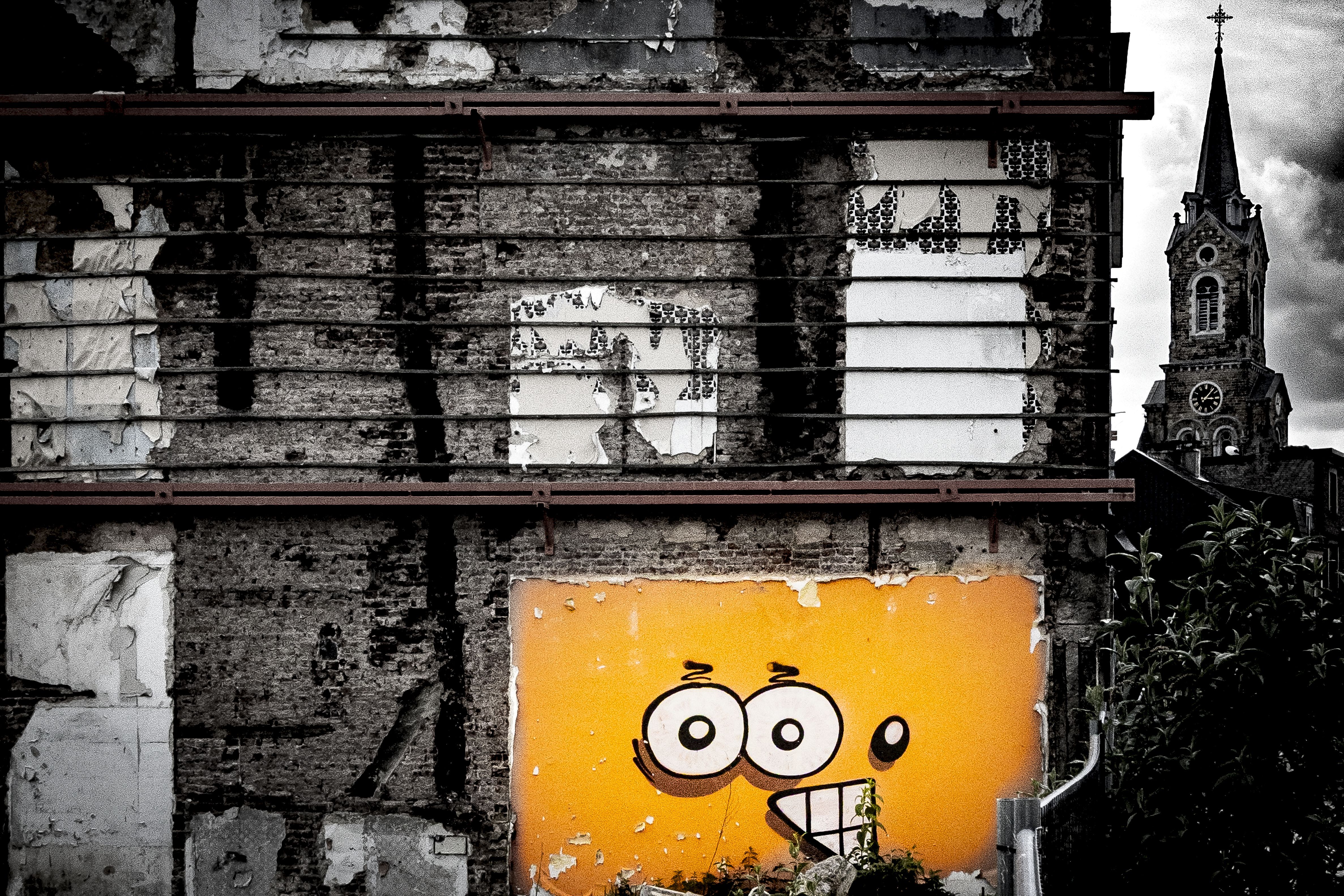 Orangefarbene Comicfigur an einer verwitterten Mauer