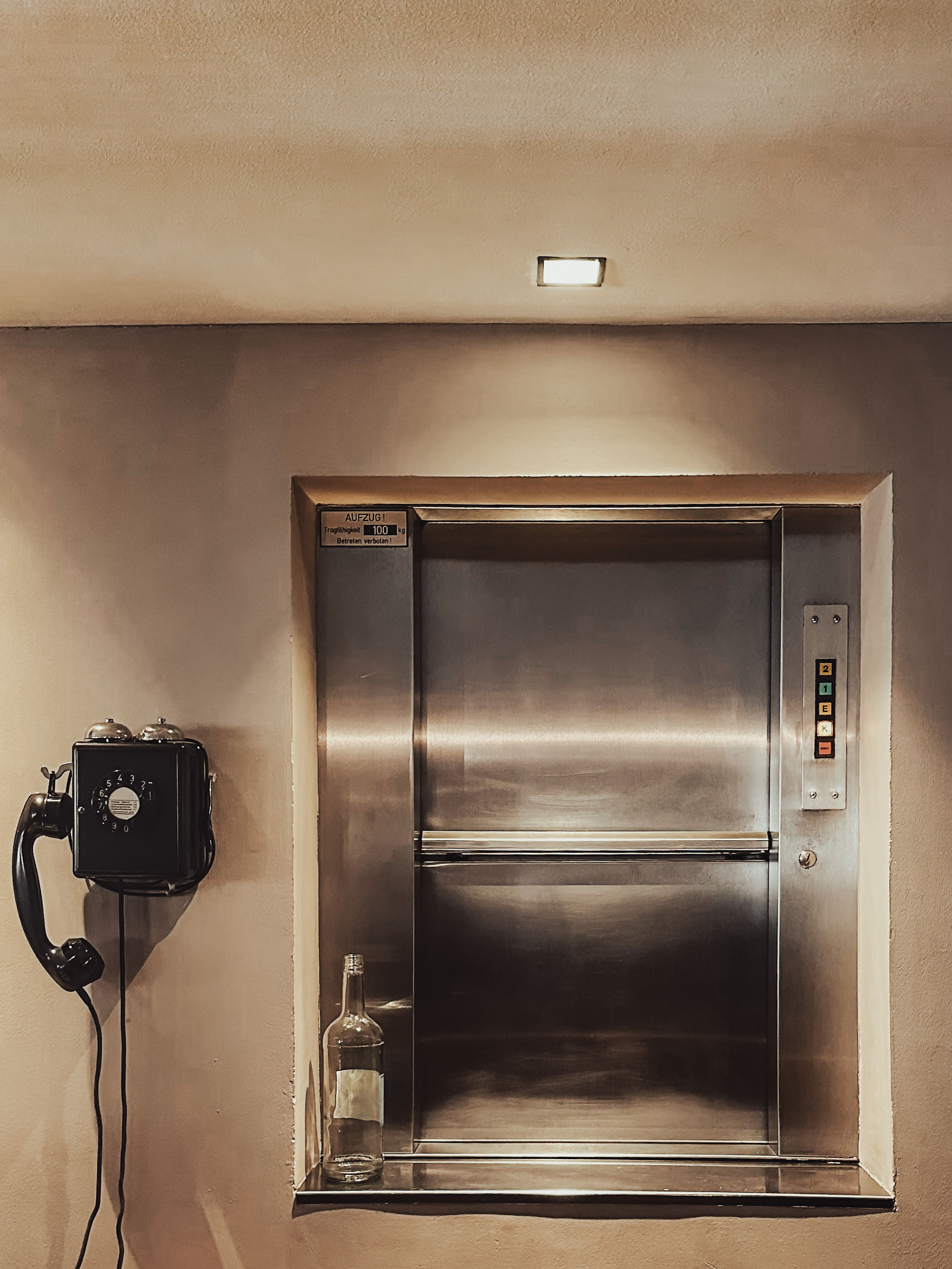 Alter Aufzug und Wandtelefon in einem stillen Flur